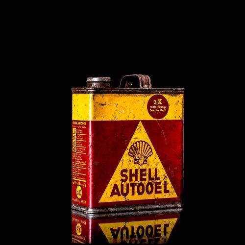 Vintage Shell oil cans with red and yellow branding from the 1900-1920 old logo Vintage Shell oil cans from 1900-19255, featuring the old logo. The photo showcases an antique tin red with yellow accents, displaying the historic Shell emblem. Shot in a studio against a solid black background