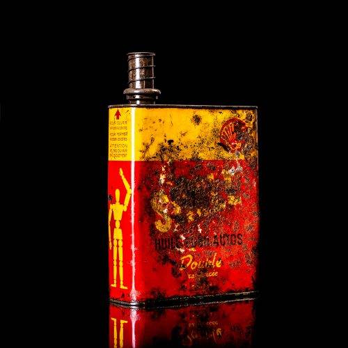 Vintage Shell oil cans with red and yellow branding from the 1900-1920 old logo Vintage Shell oil cans from 1900-19255, featuring the old logo. The photo showcases an antique tin red with yellow accents, displaying the historic Shell emblem. Shot in a studio against a solid black background