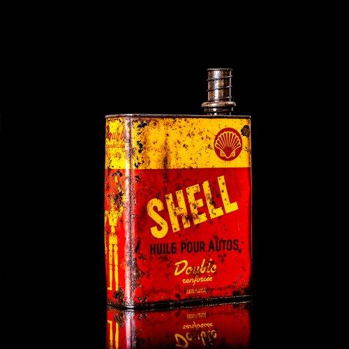 Vintage Shell oil cans with red and yellow branding from the 1900-1920 old logo Vintage Shell oil cans from 1900-19255, featuring the old logo. The photo showcases an antique tin red with yellow accents, displaying the historic Shell emblem. Shot in a studio against a solid black background