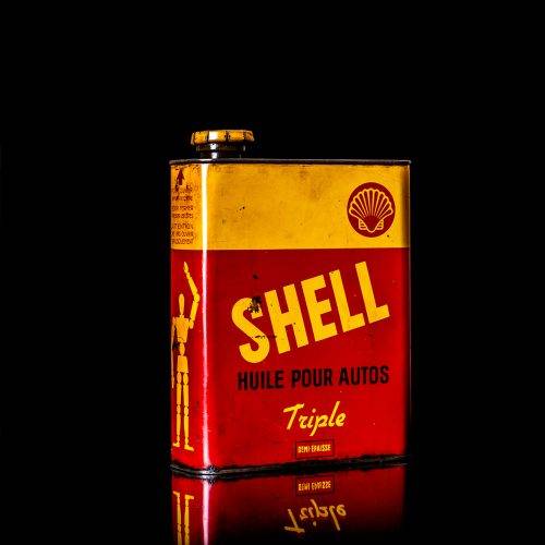Vintage Shell oil cans with red and yellow branding from the 1900-1920 old logo Vintage Shell oil cans from 1900-19255, featuring the old logo. The photo showcases an antique tin red with yellow accents, displaying the historic Shell emblem. Shot in a studio against a solid black background
