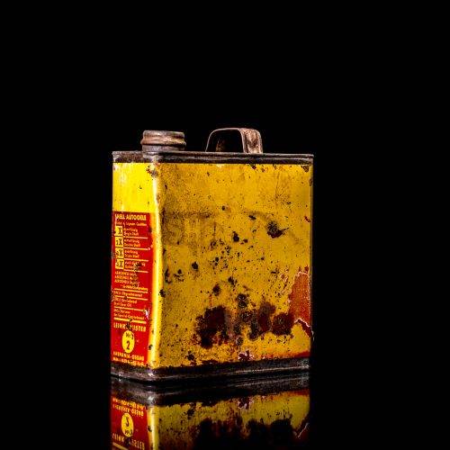 Vintage Shell oil cans with red and yellow branding from the 1900-1920 old logo Vintage Shell oil cans from 1900-19255, featuring the old logo. The photo showcases an antique tin red with yellow accents, displaying the historic Shell emblem. Shot in a studio against a solid black background