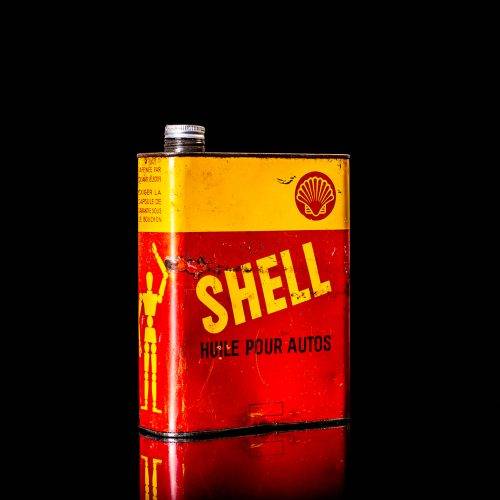 Vintage Shell oil cans with red and yellow branding from the 1900-1920 old logo Vintage Shell oil cans from 1900-19255, featuring the old logo. The photo showcases an antique tin red with yellow accents, displaying the historic Shell emblem. Shot in a studio against a solid black background