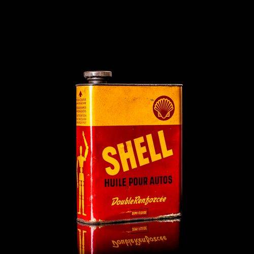 Vintage Shell oil cans with red and yellow branding from the 1900-1920 old logo Vintage Shell oil cans from 1900-19255, featuring the old logo. The photo showcases an antique tin red with yellow accents, displaying the historic Shell emblem. Shot in a studio against a solid black background