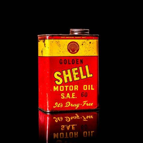 Vintage Shell oil cans with red and yellow branding from the 1900-1920 old logo Vintage Shell oil cans from 1900-19255, featuring the old logo. The photo showcases an antique tin red with yellow accents, displaying the historic Shell emblem. Shot in a studio against a solid black background