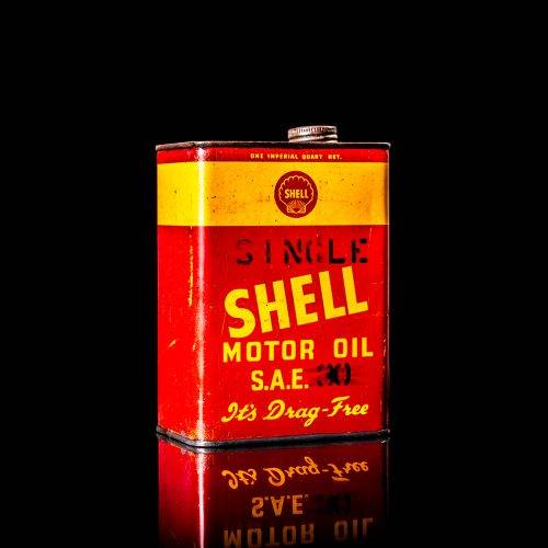 Vintage Shell oil cans with red and yellow branding from the 1900-1920 old logo Vintage Shell oil cans from 1900-19255, featuring the old logo. The photo showcases an antique tin red with yellow accents, displaying the historic Shell emblem. Shot in a studio against a solid black background