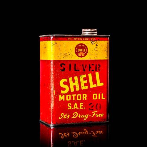 Vintage Shell oil cans with red and yellow branding from the 1900-1920 old logo Vintage Shell oil cans from 1900-19255, featuring the old logo. The photo showcases an antique tin red with yellow accents, displaying the historic Shell emblem. Shot in a studio against a solid black background