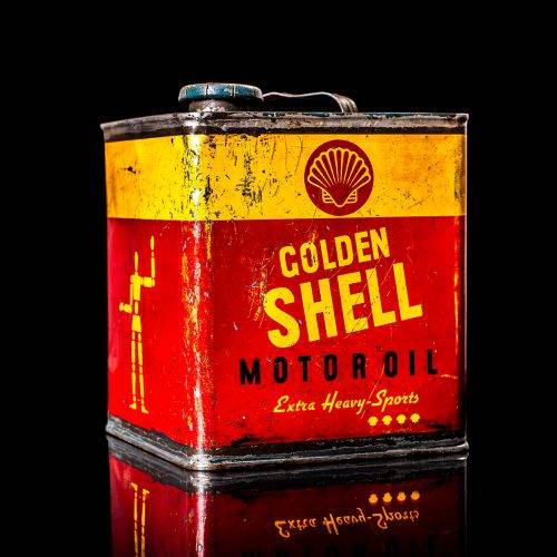 Vintage Shell oil cans with red and yellow branding from the 1900-1920 old logo Vintage Shell oil cans from 1900-19255, featuring the old logo. The photo showcases an antique tin red with yellow accents, displaying the historic Shell emblem. Shot in a studio against a solid black background