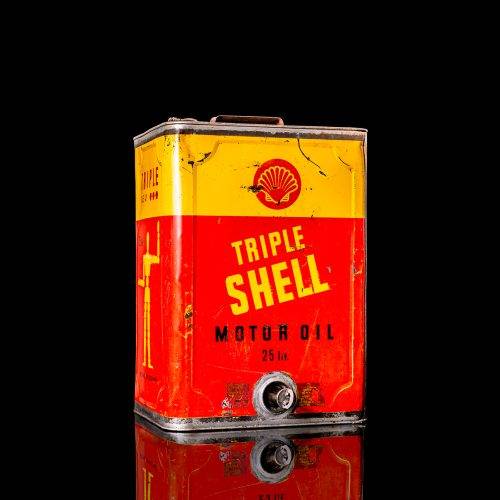 Vintage Shell oil cans with red and yellow branding from the 1900-1920 old logo Vintage Shell oil cans from 1900-19255, featuring the old logo. The photo showcases an antique tin red with yellow accents, displaying the historic Shell emblem. Shot in a studio against a solid black background