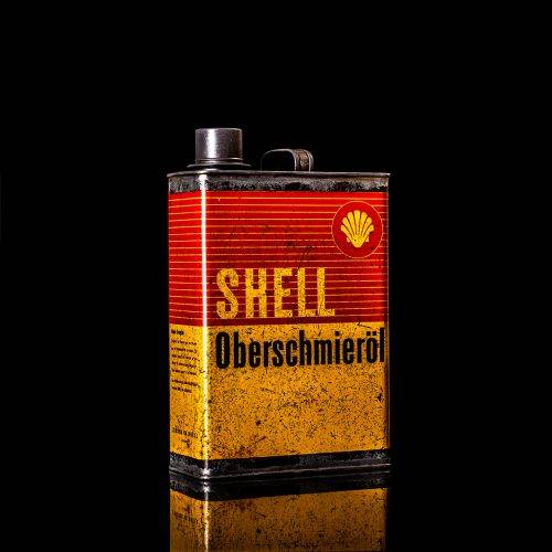 Vintage Shell oil cans with red and yellow branding from the 1900-1920 old logo Vintage Shell oil cans from 1900-19255, featuring the old logo. The photo showcases an antique tin red with yellow accents, displaying the historic Shell emblem. Shot in a studio against a solid black background