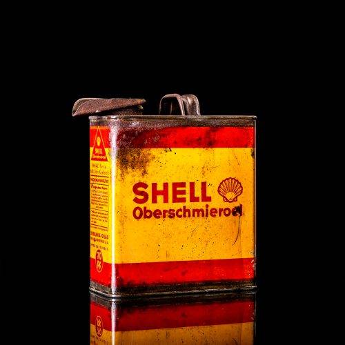 Vintage Shell oil cans with red and yellow branding from the 1900-1920 old logo Vintage Shell oil cans from 1900-19255, featuring the old logo. The photo showcases an antique tin red with yellow accents, displaying the historic Shell emblem. Shot in a studio against a solid black background