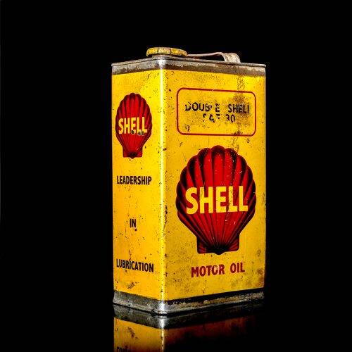 Vintage Shell oil cans with red and yellow branding from the 1900-1920 old logo Vintage Shell oil cans from 1900-19255, featuring the old logo. The photo showcases an antique tin red with yellow accents, displaying the historic Shell emblem. Shot in a studio against a solid black background