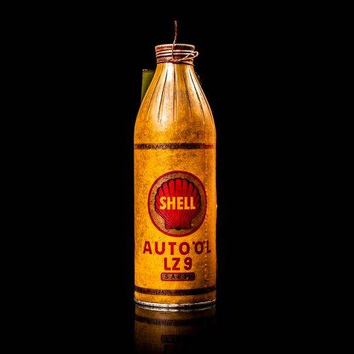 Vintage Shell oil cans with red and yellow branding from the 1900-1920 old logo Vintage Shell oil cans from 1900-19255, featuring the old logo. The photo showcases an antique tin red with yellow accents, displaying the historic Shell emblem. Shot in a studio against a solid black background