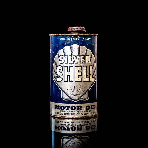 Vintage Shell oil cans with red and yellow branding from the 1900-1920 old logo Vintage Shell oil cans from 1900-19255, featuring the old logo. The photo showcases an antique tin red with yellow accents, displaying the historic Shell emblem. Shot in a studio against a solid black background