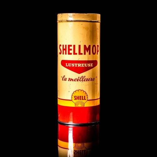 Vintage Shell oil can from 1950–1960 with white base color, yellow and red accents, and the classic Shell logo. Antique motor oil tin displayed in a studio setting against a solid black background."