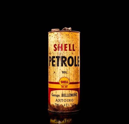 Vintage Shell oil cans with red and yellow branding from the 1900-1920 old logo Vintage Shell oil cans from 1900-19255, featuring the old logo. The photo showcases an antique tin red with yellow accents, displaying the historic Shell emblem. Shot in a studio against a solid black background