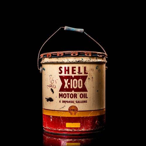 Vintage Shell oil cans with red and yellow branding from the 1900-1920 old logo Vintage Shell oil cans from 1900-19255, featuring the old logo. The photo showcases an antique tin red with yellow accents, displaying the historic Shell emblem. Shot in a studio against a solid black background