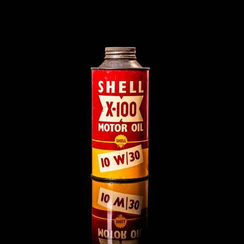 Vintage Shell oil cans with red and yellow branding from the 1900-1920 old logo Vintage Shell oil cans from 1900-19255, featuring the old logo. The photo showcases an antique tin red with yellow accents, displaying the historic Shell emblem. Shot in a studio against a solid black background