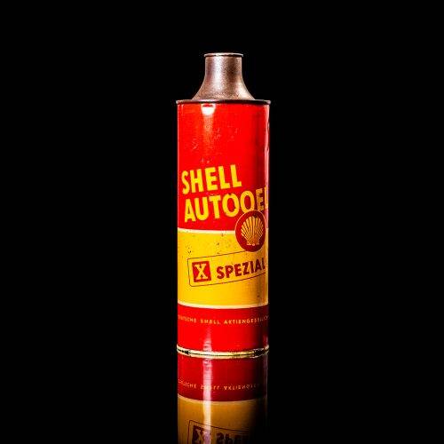 Vintage Shell oil cans with red and yellow branding from the 1900-1920 old logo Vintage Shell oil cans from 1900-19255, featuring the old logo. The photo showcases an antique tin red with yellow accents, displaying the historic Shell emblem. Shot in a studio against a solid black background