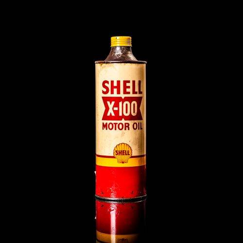Vintage Shell oil cans with red and yellow branding from the 1900-1920 old logo Vintage Shell oil cans from 1900-19255, featuring the old logo. The photo showcases an antique tin red with yellow accents, displaying the historic Shell emblem. Shot in a studio against a solid black background