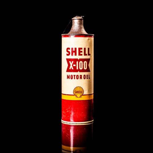 Vintage Shell oil can from 1950–1960 with white base color, yellow and red accents, and the classic Shell logo. Antique motor oil tin displayed in a studio setting against a solid black background."