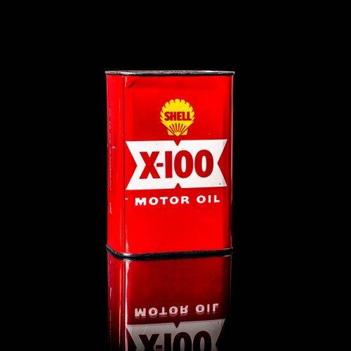 Vintage Shell oil can from 1950–1960 with white base color, yellow and red accents, and the classic Shell logo. Antique motor oil tin displayed in a studio setting against a solid black background."