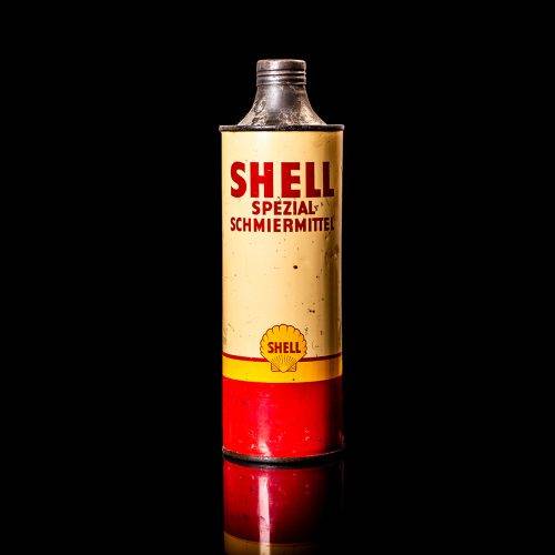 Vintage Shell oil can from 1950–1960 with white base color, yellow and red accents, and the classic Shell logo. Antique motor oil tin displayed in a studio setting against a solid black background."