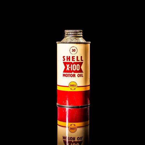 Vintage Shell oil cans with red and yellow branding from the 1900-1920 old logo Vintage Shell oil cans from 1900-19255, featuring the old logo. The photo showcases an antique tin red with yellow accents, displaying the historic Shell emblem. Shot in a studio against a solid black background