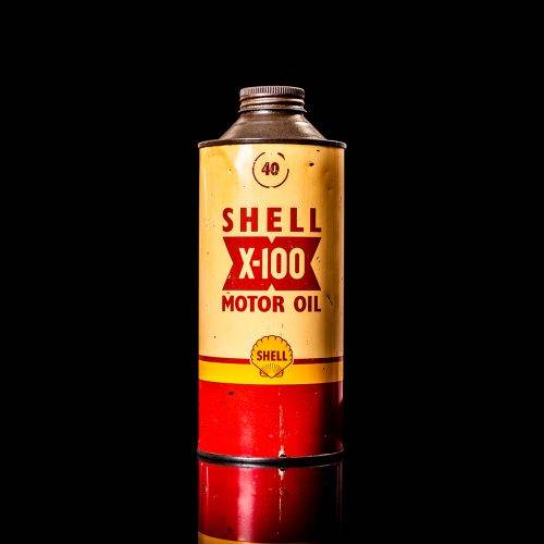 Vintage Shell oil cans with red and yellow branding from the 1900-1920 old logo Vintage Shell oil cans from 1900-19255, featuring the old logo. The photo showcases an antique tin red with yellow accents, displaying the historic Shell emblem. Shot in a studio against a solid black background