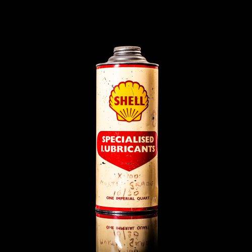 Vintage Shell oil cans with red and yellow branding from the 1900-1920 old logo Vintage Shell oil cans from 1900-19255, featuring the old logo. The photo showcases an antique tin red with yellow accents, displaying the historic Shell emblem. Shot in a studio against a solid black background