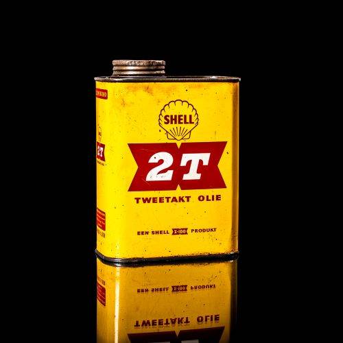 Vintage Shell oil can from 1950–1960 with white base color, yellow and red accents, and the classic Shell logo. Antique motor oil tin displayed in a studio setting against a solid black background."