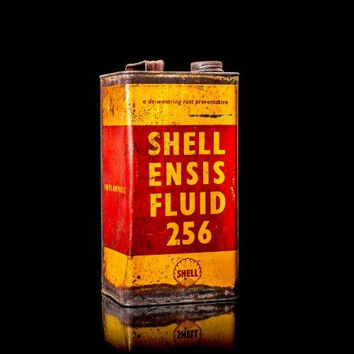 Vintage Shell oil can from 1950–1960 with white base color, yellow and red accents, and the classic Shell logo. Antique motor oil tin displayed in a studio setting against a solid black background."