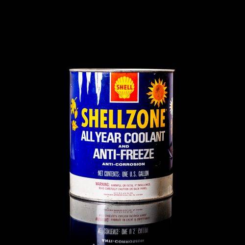 Vintage Shell oil can from 1950–1960 with white base color, yellow and red accents, and the classic Shell logo. Antique motor oil tin displayed in a studio setting against a solid black background."