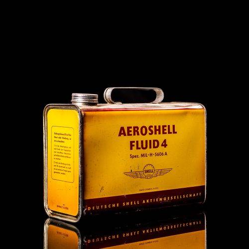 Vintage Shell oil can from 1950–1960 with white base color, yellow and red accents, and the classic Shell logo. Antique motor oil tin displayed in a studio setting against a solid black background."