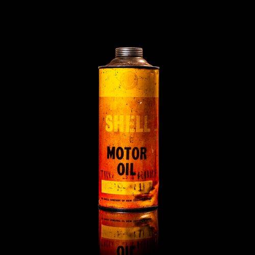 Vintage Shell oil cans with red and yellow branding from the 1900-1920 old logo Vintage Shell oil cans from 1900-19255, featuring the old logo. The photo showcases an antique tin red with yellow accents, displaying the historic Shell emblem. Shot in a studio against a solid black background