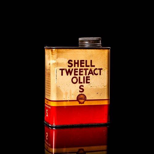 Vintage Shell oil can from 1950–1960 with white base color, yellow and red accents, and the classic Shell logo. Antique motor oil tin displayed in a studio setting against a solid black background."