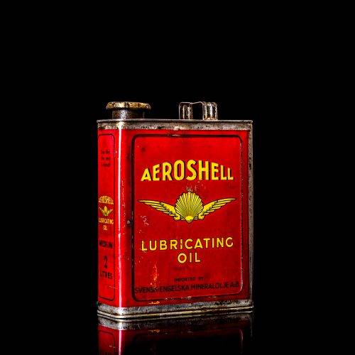 Vintage Shell oil cans with red and yellow branding from the 1900-1920 old logo Vintage Shell oil cans from 1900-19255, featuring the old logo. The photo showcases an antique tin red with yellow accents, displaying the historic Shell emblem. Shot in a studio against a solid black background