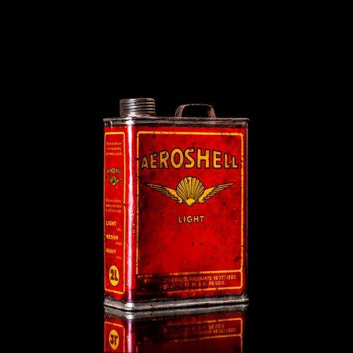 Vintage Shell oil cans with red and yellow branding from the 1900-1920 old logo Vintage Shell oil cans from 1900-19255, featuring the old logo. The photo showcases an antique tin red with yellow accents, displaying the historic Shell emblem. Shot in a studio against a solid black background