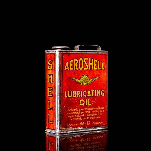 Rare and unique vintage Aeroshell oil can from 1900–1950 with red base and yellow accents, featuring the aeroShell logo. This antique motor oil tin is displayed in a studio setting against a solid black background.