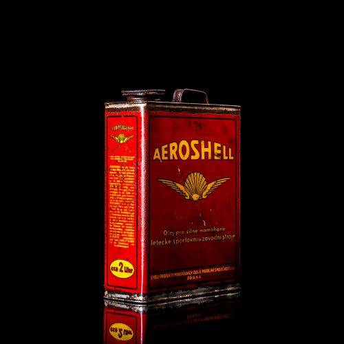 Vintage Shell oil cans with red and yellow branding from the 1900-1920 old logo Vintage Shell oil cans from 1900-19255, featuring the old logo. The photo showcases an antique tin red with yellow accents, displaying the historic Shell emblem. Shot in a studio against a solid black background