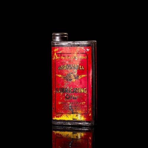 Rare and unique vintage Aeroshell oil can from 1900–1950 with red base and yellow accents, featuring the aeroShell logo. This antique motor oil tin is displayed in a studio setting against a solid black background.