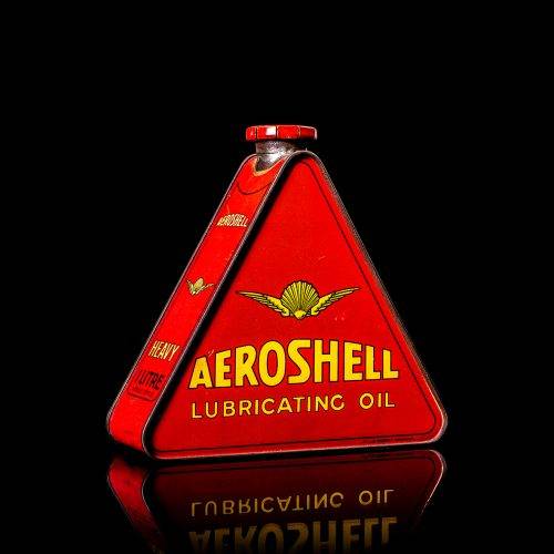 Rare and unique vintage Aeroshell oil can from 1900–1950 with red base and yellow accents, featuring the aeroShell logo. This antique motor oil tin is displayed in a studio setting against a solid black background.