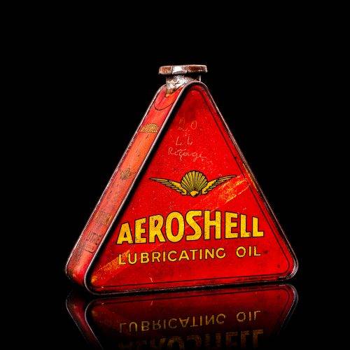 Rare and unique vintage Aeroshell oil can from 1900–1950 with red base and yellow accents, featuring the aeroShell logo. This antique motor oil tin is displayed in a studio setting against a solid black background.