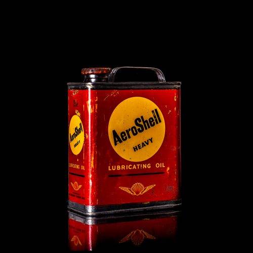 Vintage Shell oil cans with red and yellow branding from the 1900-1920 old logo Vintage Shell oil cans from 1900-19255, featuring the old logo. The photo showcases an antique tin red with yellow accents, displaying the historic Shell emblem. Shot in a studio against a solid black background