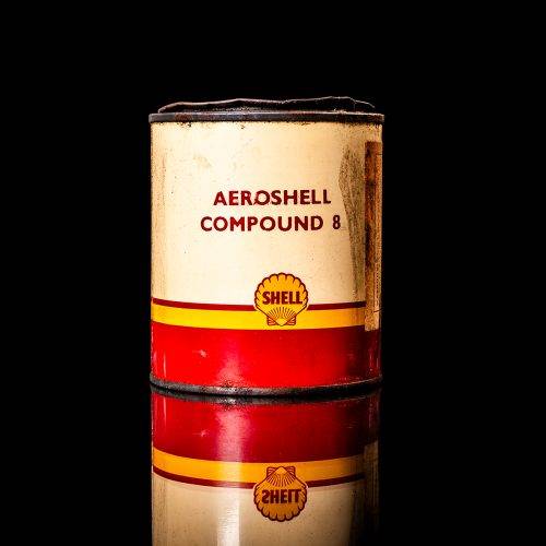 Rare and unique vintage Aeroshell oil can from 1900–1950 with red base and yellow accents, featuring the aeroShell logo. This antique motor oil tin is displayed in a studio setting against a solid black background.