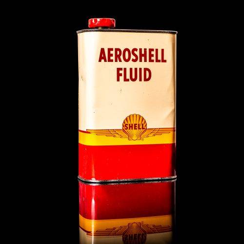Rare and unique vintage Aeroshell oil can from 1900–1950 with red base and yellow accents, featuring the aeroShell logo. This antique motor oil tin is displayed in a studio setting against a solid black background.