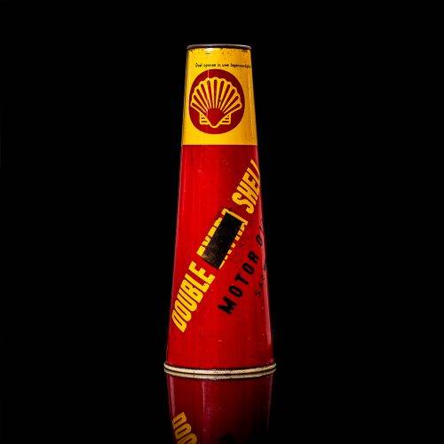 Vintage Shell oil cans with red and yellow branding from the 1900-1920 old logo Vintage Shell oil cans from 1900-19255, featuring the old logo. The photo showcases an antique tin red with yellow accents, displaying the historic Shell emblem. Shot in a studio against a solid black background