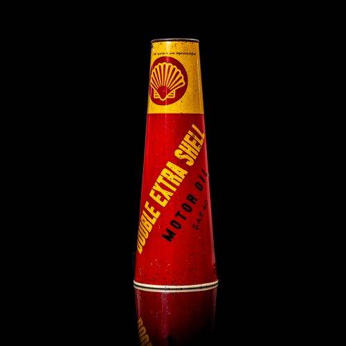 Rare and unique vintage conical shell oil can from 1900–1950 with a red base and yellow accents, featuring the classic shell logo. This antique, cone-shaped motor oil tin is showcased in a studio setting against a solid black background.