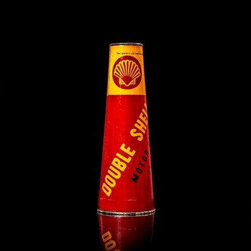 Rare and unique vintage conical shell oil can from 1900–1950 with a red base and yellow accents, featuring the classic shell logo. This antique, cone-shaped motor oil tin is showcased in a studio setting against a solid black background.