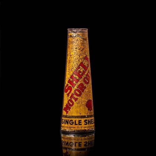 Rare and unique vintage conical shell oil can from 1900–1950 with a red base and yellow accents, featuring the classic shell logo. This antique, cone-shaped motor oil tin is showcased in a studio setting against a solid black background.