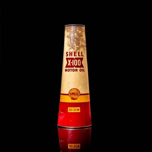 Rare and unique vintage conical shell oil can from 1900–1950 with a red base and yellow accents, featuring the classic shell logo. This antique, cone-shaped motor oil tin is showcased in a studio setting against a solid black background.